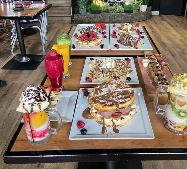 Waffles, crepes and milkshakes on a table inside Sasa Cafe